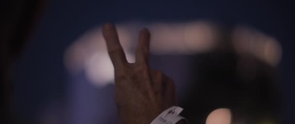 A man waving a hand with victory sign during a political riot at night. Slow motion, close up. - Materiał filmowy, wideo