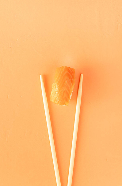 Минимальная концепция. суши с лососем и палочками, изолированные на оранжевом фоне. Вид сверху. Плоский лежал - Фото, изображение