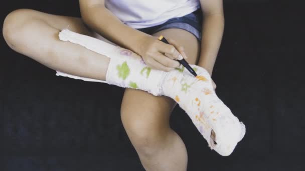 A adolescente desenha em uma perna em um molde. Uma maneira de se divertir com uma perna quebrada.Fratura do pé. Perna partida - Filmagem, Vídeo