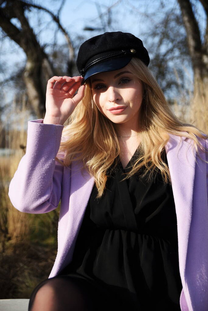 ヴロツワフ市の若い女性。ブロンドの髪の女性学生,紫色のコートと黒の帽子を身に着けている. - 写真・画像