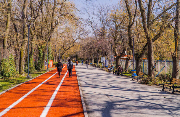 Ankara, Turcja - 12 marca 2021 r. - widok dzienny na ludzi spacerujących po torze biegowym w parku Independence Park (Kurtulus Park) w słoneczny dzień - Zdjęcie, obraz