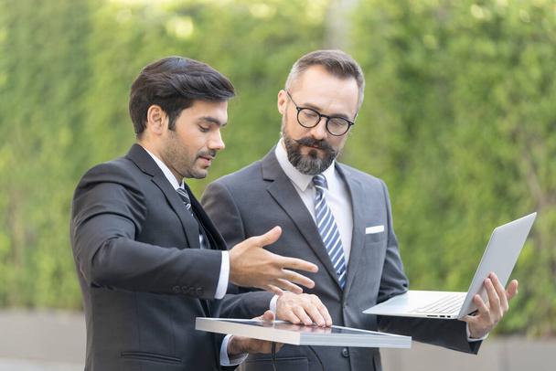 Handsome businessman and Engineer attractive. Businessman and attractive Engineer talking and holding laptop and solar panel. at outside office. - Photo, Image