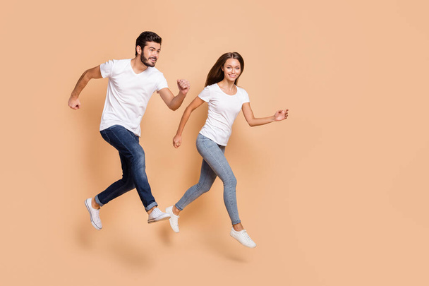 Full body profile side photo of young couple happy smile jump go run hurry sale isolated over beige color background - Valokuva, kuva