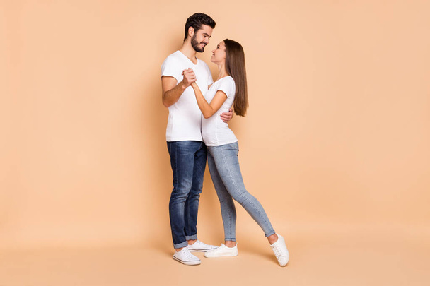 Full body profile side photo of young couple happy positive smile hug hold hands dance romantic isolated over beige color background - Valokuva, kuva