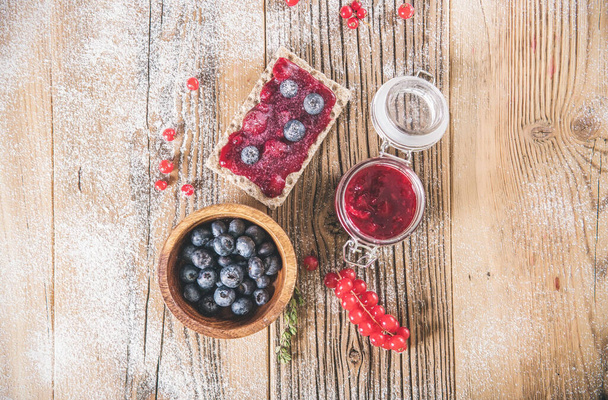 Украшенный сладкий завтрак с ягодами и тостами над деревянным столом. Вкусная здоровая сладкая еда, вид сверху - Фото, изображение