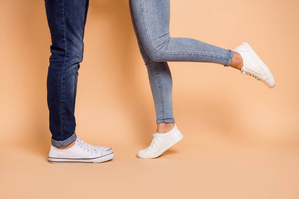 Cropped photo of girlfriend boyfriend legs in jeans sneakers date romantic feelings isolated over beige color background - Foto, imagen