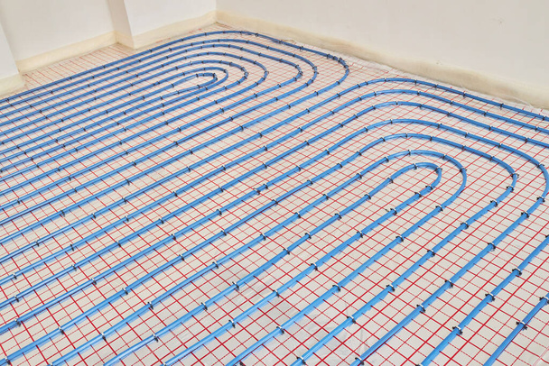 Μπλε πλαστικοί σωλήνες ενδοδαπέδια θέρμανση σε εσωτερικό χώρο ενός νέου σπιτιού. Ενδοδαπέδια θέρμανση.  - Φωτογραφία, εικόνα
