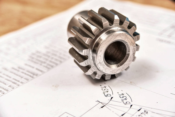 A cogwheel made on a gear cutting machine lies on the technical drawings - Photo, Image