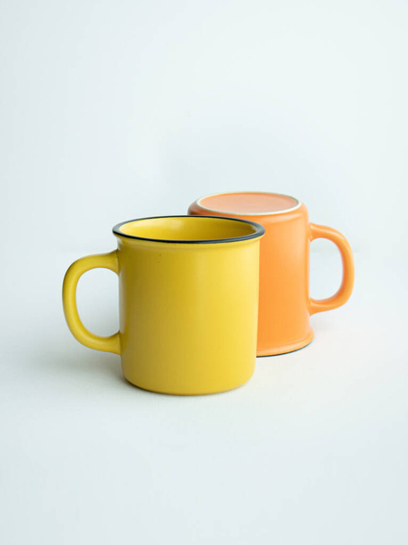 Κεραμική κούπα κίτρινη και πορτοκαλί σε λευκό φόντο, Τοποθέτηση - Φωτογραφία, εικόνα
