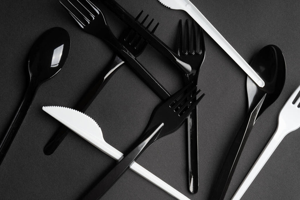Forks and spoons on gray background. Plastic cutlery, ecology, environmental pollution by plastic, disposable tableware, waste recycling concept. copyspace, flat lay. - Photo, Image