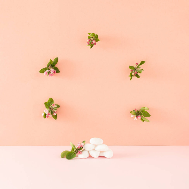 Vitrine criativa feita com rochas brancas e flores floridas contra um fundo rosa e laranja. Mock-up romântico mínimo para produtos ou espaço de cópia. - Foto, Imagem