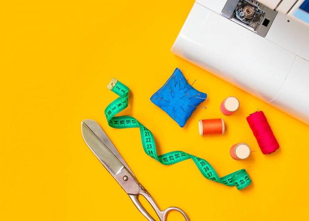 Sewing accessories. Composition with threads and sewing accessories on yellow background. Workplace of seamstress.Top view, copy space, flat lay, mock up - Photo, Image