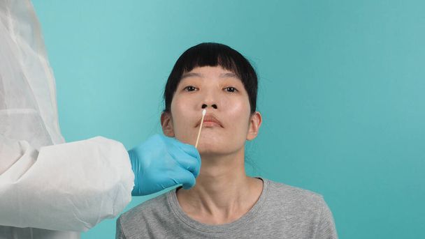 Τεστ δειγμάτων Covid 19. γυναίκα με PCR δοκιμή. Δοκιμή του κορωναϊού κατά τη διάρκεια επιδημίας. Γιατρός που παίρνει δείγμα για δοκιμή ιού. στούντιο πυροβόλησε και μπλε πράσινο φόντο. Γιατρός σε PPE δοκιμή μάκτρο κοστούμι. - Φωτογραφία, εικόνα