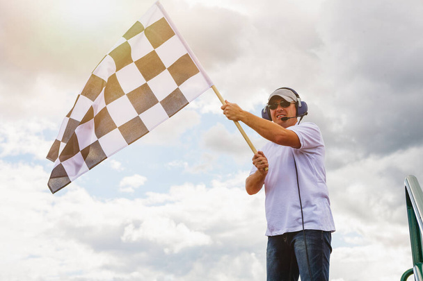Homem acena uma bandeira quadriculada na linha de chegada da corrida - Foto, Imagem