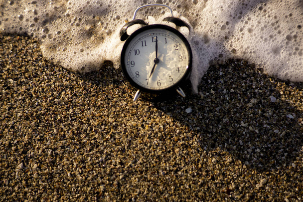 Reloj despertador salpicando en el agua de la playa - Foto, imagen