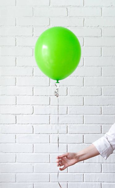 hand holds the green balloon on the ribbon. - Zdjęcie, obraz