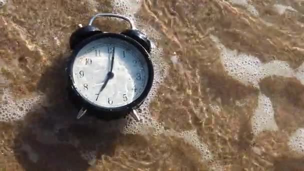 Budzik rozbryzga się w wodzie na plaży - Materiał filmowy, wideo