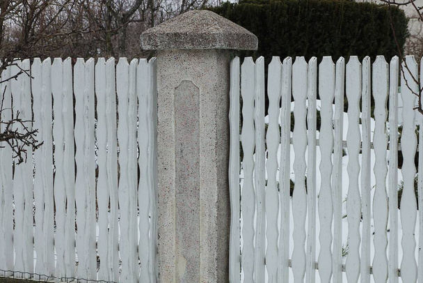 część ściany ogrodzenia z białych drewnianych desek i słupka z szarego betonu na ulicy - Zdjęcie, obraz