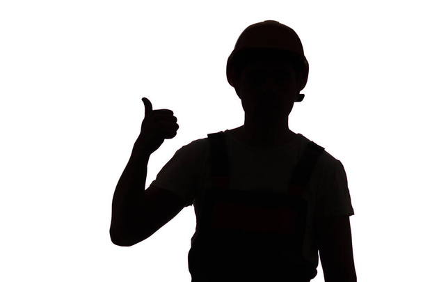 Young construction worker silhouette in hard hat showing thumbs up class sign on white isolated studio background - Foto, immagini