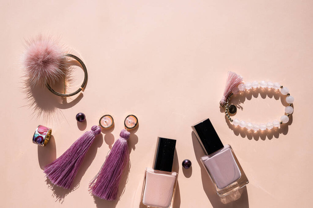 Flat lay for fashion blog and social media. Womans glamour beauty accessories on pastel background. nail polish, lipstick, jewelry. Womans Jewellery.Modern earrings and bracelets.Copy space - Photo, Image