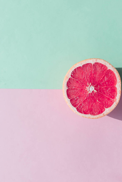 Свежий нарезанный спелый Грейпфрут на зеленом и розовом фоне, вид сверху. Плоский дизайн и концепция лемонады Vegan Arph. Творческий летний фон. - Фото, изображение