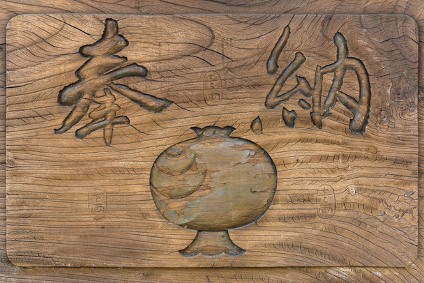 tokyo, japan - april 07 2020: Close up on a wooden cracked board adorned with the symbol of magic mallet of Daikokuten god and two carved Japanese kanji ideograms meaning votive offering in a shrine. - Foto, afbeelding