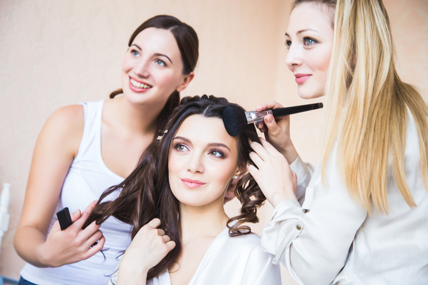 Stylist and makeup artist preparing bride before the wedding in a morning - Foto, Bild