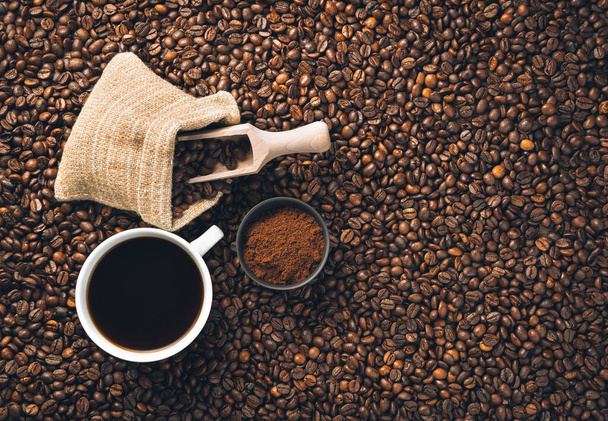 地上のコーヒー、コーヒー豆と散乱コーヒー豆のコーヒーカップ。トップビュー、水平. - 写真・画像