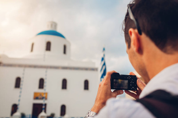 Voyageur Santorin prendre une photo de l'église avec dôme bleu et drapeau à Oia, Grèce sur la caméra. Tourisme, voyages, vacances d'été. Architecture traditionnelle - Photo, image