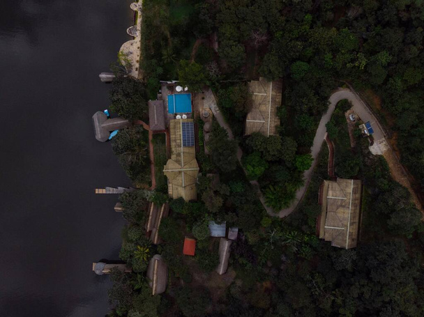 Letecký panorama pohled na Amazon tropický deštný prales exotický svěží džungle eco lodge hotel dřevěná kabina chůdy chata u řeky jezera v Jižní Americe - Fotografie, Obrázek