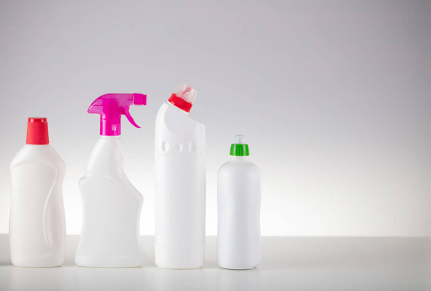 Házi és irodai takarítás téma. Fehér palack készlet, fehér alapon tapadó folyadékkal. - Fotó, kép