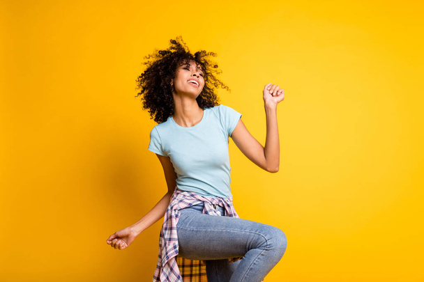 Photo of charming funky dark skin curly girl dressed blue t-shirt dancing isolated yellow color background - Fotografie, Obrázek