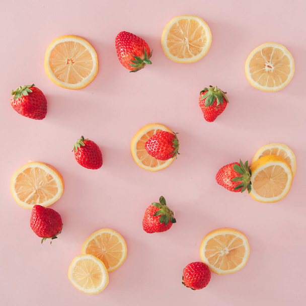 Delicate flat lay background. Lemon and strawberries on  pastel pink background. - Foto, afbeelding