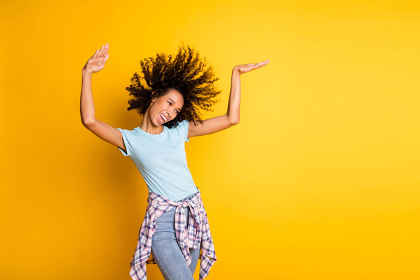 Photo of funny adorable dark skin wavy lady wear blue t-shirt dancing empty space isolated yellow color background - Valokuva, kuva