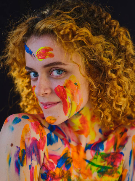 Redhead Girl with multi-colored paints on her face and body - Photo, Image