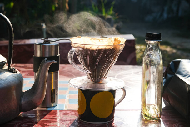 Капельное варка кофе на бумаге фильтруется на столе утром на открытом воздухе дома - Фото, изображение