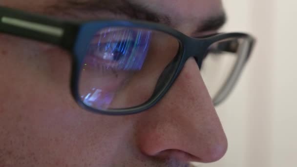 Macro en el ojo de un ingeniero de software que está trabajando: la mirada enfocada en la pantalla, en la lente de las gafas vemos el reflejo. Imagen clara y cristalina en la lente derecha. Enfoque selectivo - Metraje, vídeo
