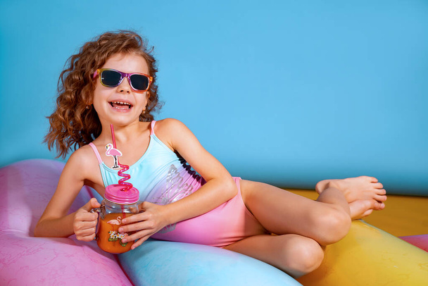 Beautiful girl in colorful swimsuit and sunglasses holding pinea - Valokuva, kuva