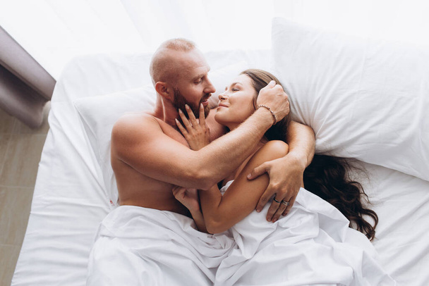 Loving couple in bed on white sheets. Stay at home. - Photo, image