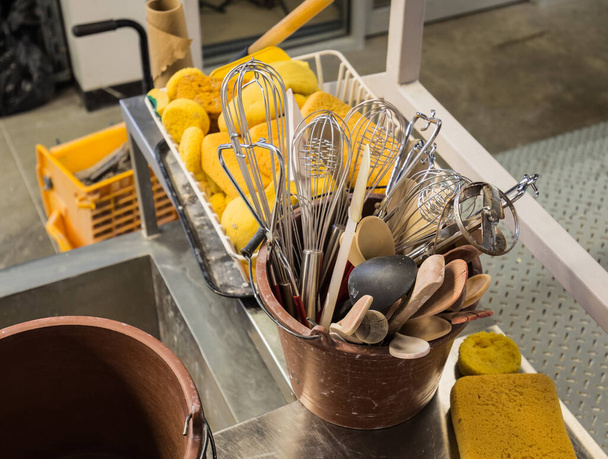 Вид крупным планом на старые использованные кухонные инструменты, губки, сложенные в пластиковые ведра для художественного исполнения, мастерская  - Фото, изображение