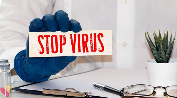 Steteskoplu bir masada üzerinde STOP VIRUS yazan kağıt. Tıbbi konsept. - Fotoğraf, Görsel