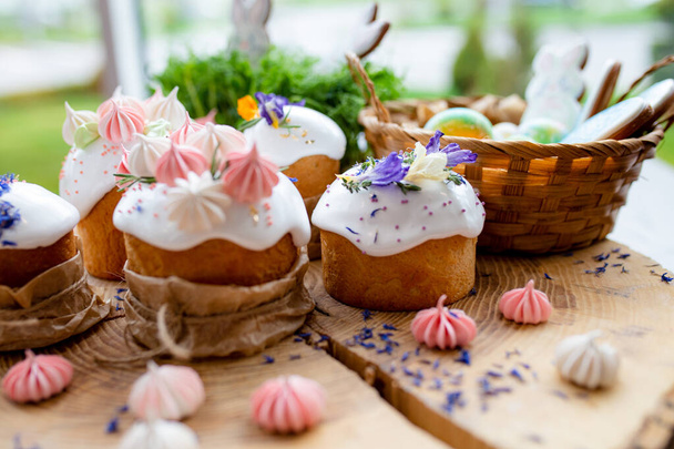Ortodoks Paskalya 2021. Pasta dekorasyonu. Beyaz kremalı kekler, pembe ve beyaz kremayla süslenmiş, çiçekler ve doğal ahşap arka planda bitkiler. Paskalya kartı. - Fotoğraf, Görsel