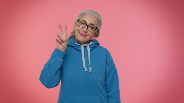 Grand-mère mature montrant le signe de victoire, espérant le succès et la victoire, faisant le geste de paix, souriant - Séquence, vidéo