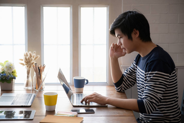 Asyalı erkek öğrenci evdeki oturma odasında internetten öğrenme ve dizüstü bilgisayarla video dersi izleyerek odaklanıyor. çevrimiçi sınıf konsepti. - Fotoğraf, Görsel