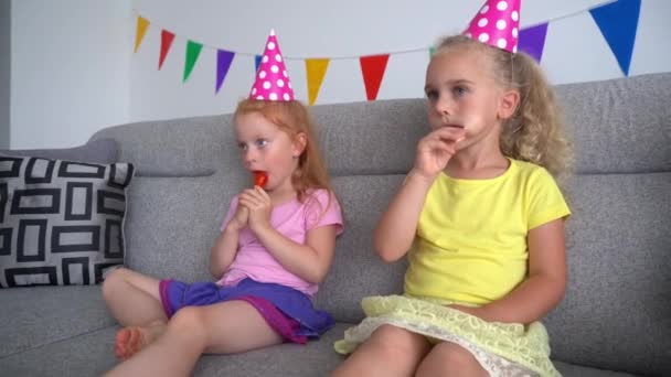 happy girls watching tv and eating sweets candies on sticks at home - Footage, Video