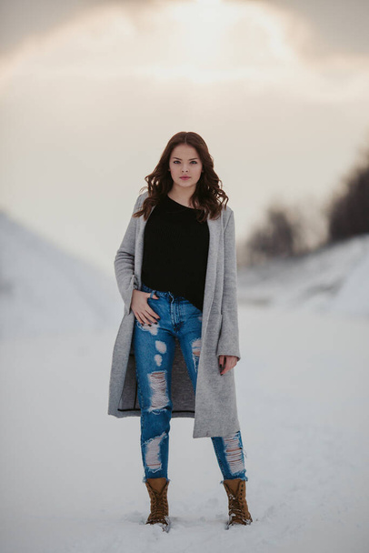 A vertical shot of a young female model posing in a jacket and ripped jeans - Foto, imagen