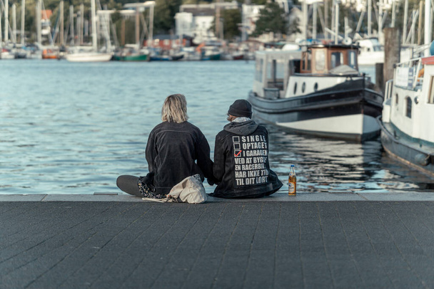 FLENSBURG, GERMANY - Jul 11, 2020: Joung couple sitting at the port next to the sea in Flensburg - Foto, Bild