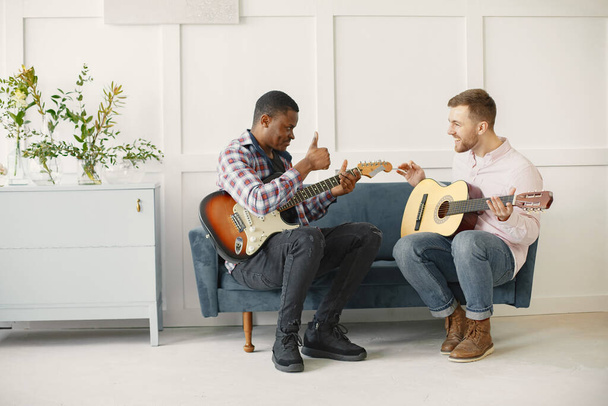 African man and Caucasian man playing guitar - Fotó, kép