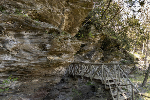 A wooden staircase and bridge in a forest leading into a cave - Fotó, kép