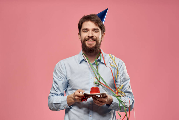 Homme avec gâteau dans une assiette et dans une chemise bleue sur un fond rose anniversaire vacances vue recadrée - Photo, image